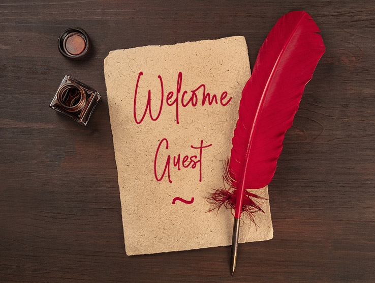 red quill pen on a piece of old parchment paper, with an ink well with words Welcome Guest in script